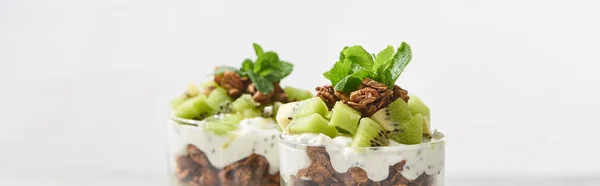 Selective focus of fresh granola with kiwi and yogurt isolated on grey, panoramic shot — Stock Photo