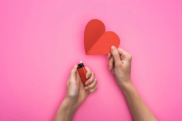Cropped view of woman lighting up empty red paper heart with lighter isolated on pink — Stock Photo