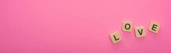 Top view of wooden blocks with love lettering isolated on pink, panoramic shot — Stock Photo