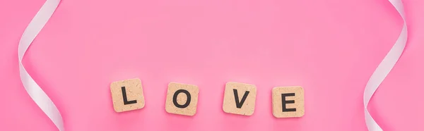 Vista superior de fitas curvas e blocos de madeira com letras de amor isolado em rosa, tiro panorâmico — Fotografia de Stock