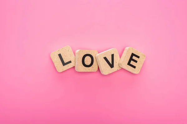 Top view of love lettering on wooden cubes isolated on pink — Stock Photo