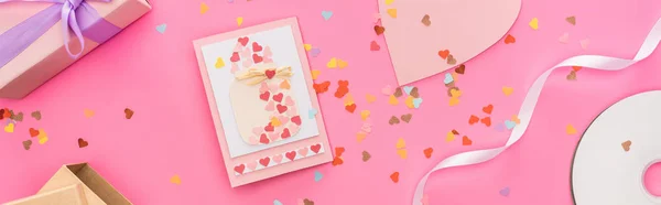 Top view of valentines confetti, empty compact disk, gift boxes, greeting card on pink background, panoramic shot — Stock Photo