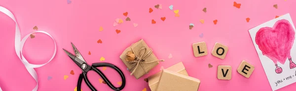 Konfetti, Scheren, Geschenkschachteln, Grußkarte und Liebesaufdruck auf Holzwürfeln auf rosa Hintergrund, Panoramaaufnahme — Stockfoto