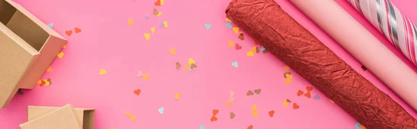 Vue du dessus des confettis de Saint-Valentin, papier d'emballage, boîtes-cadeaux sur fond rose, vue panoramique — Photo de stock