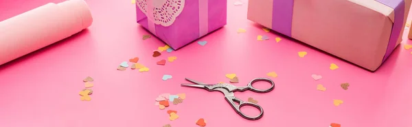 Confettis de Saint-Valentin, ciseaux, papier d'emballage, boîtes-cadeaux sur fond rose, vue panoramique — Photo de stock