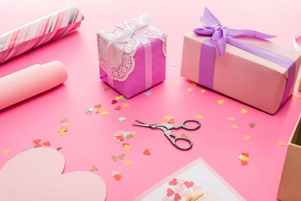 Valentines confetti, scissors, wrapping paper, gift boxes on pink background — Stock Photo