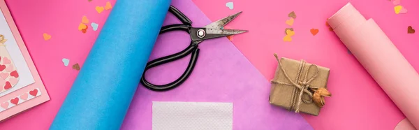 Top view of valentines decoration, wrapping paper, gift box, scissors on pink background, panoramic shot — Stock Photo