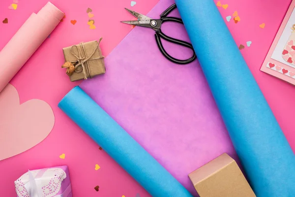 Confeti de San Valentín, tijeras, tarjeta de felicitación, papel de regalo, caja de regalo sobre fondo rosa - foto de stock