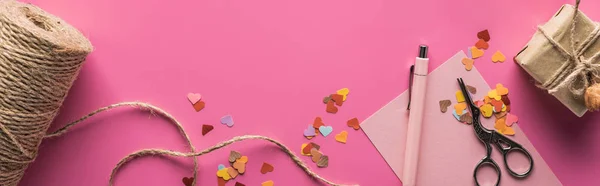 Вид зверху прикраси валентинки, ножиці, подарункова коробка, шпагат і любовне написання на дерев'яних кубиках на рожевому фоні, панорамний знімок — стокове фото