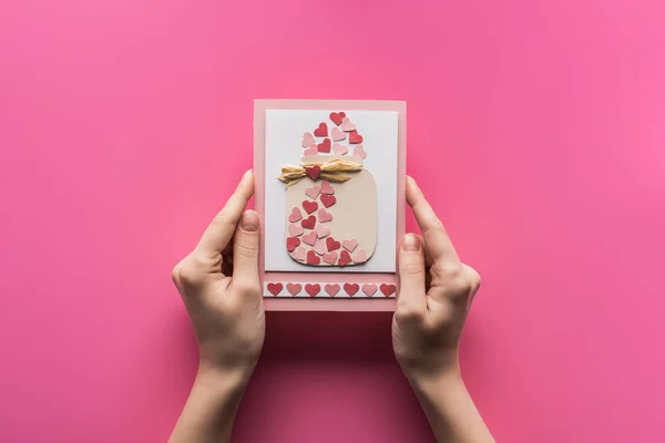 Vista recortada de la mujer sosteniendo tarjeta de felicitación de San Valentín aislado en rosa - foto de stock