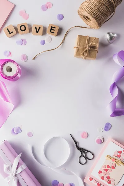 Vista superior da decoração dos namorados, presentes, suprimentos de mão-de-obra e letras de amor em cubos no fundo branco — Fotografia de Stock