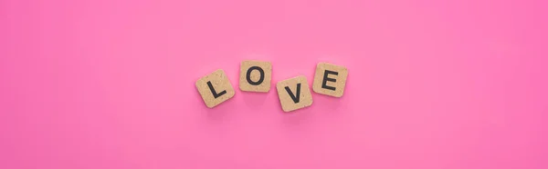 Top view of love lettering on wooden cubes on pink background, panoramic shot — Stock Photo