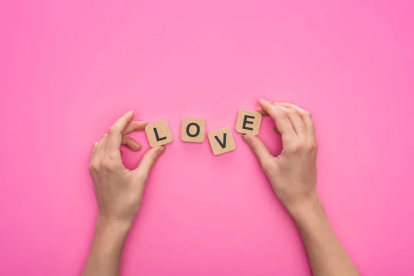Teilansicht einer Frau, die Würfel mit Liebesschrift auf rosa Hintergrund hält — Stockfoto