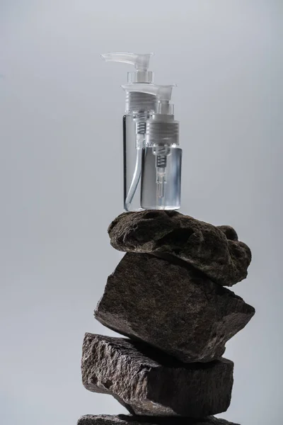 Dispensador de botellas de cosméticos en piedras aisladas en gris - foto de stock