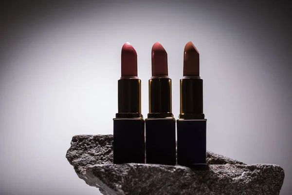 Lipsticks on stone in dark on white background with back light — Stock Photo