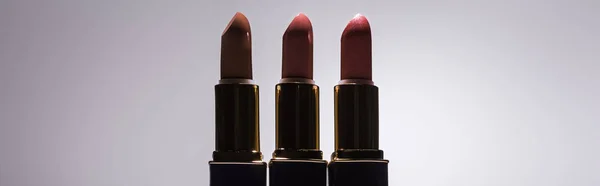 Lippenstifte im Dunkeln auf weißem Hintergrund mit Gegenlicht, Panoramaaufnahme — Stockfoto