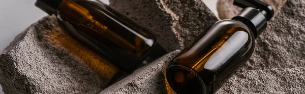 Dispensador de botellas de cosméticos en rocas aisladas en gris, plano panorámico - foto de stock