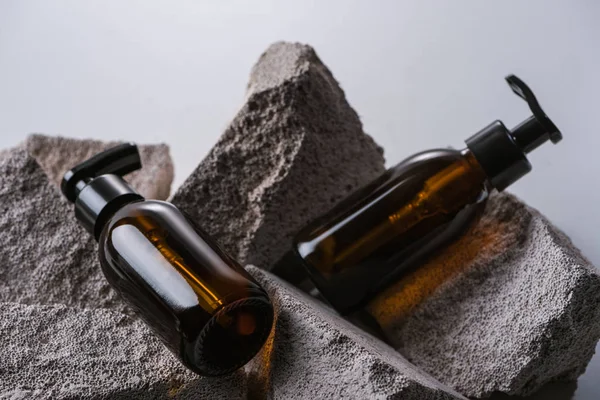 Dispenser cosmetic bottles on rocks isolated on grey — Stock Photo