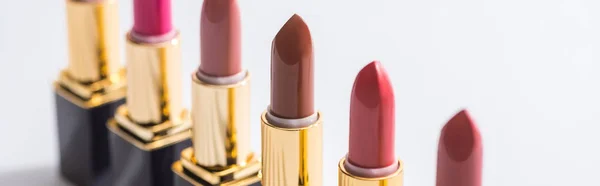 Selective focus of assorted lipsticks in luxury tubes in line on white background, panoramic shot — Stock Photo