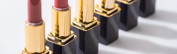 Close up view of assorted lipsticks in luxury tubes in line on white background, panoramic shot — Stock Photo