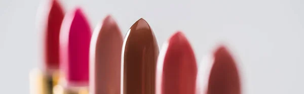 Close up view of assorted lipsticks in luxury tubes in line on white background, panoramic shot — Stock Photo