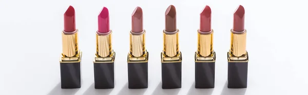 Assorted lipsticks in luxury tubes in line on white background, panoramic shot — Stock Photo