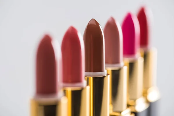Vue rapprochée de rouges à lèvres assortis dans des tubes de luxe en ligne isolés sur fond blanc — Photo de stock