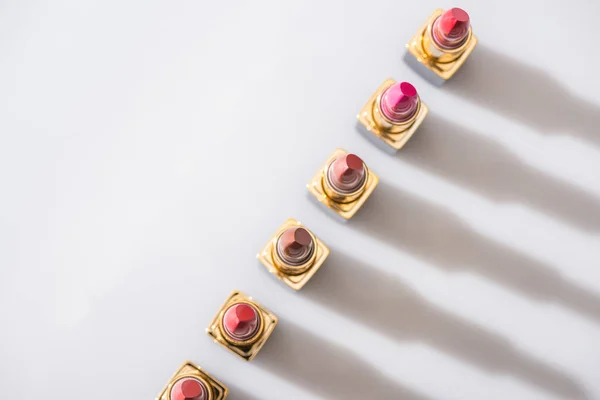 Top view of assorted lipsticks in luxury tubes in line on white background — Stock Photo