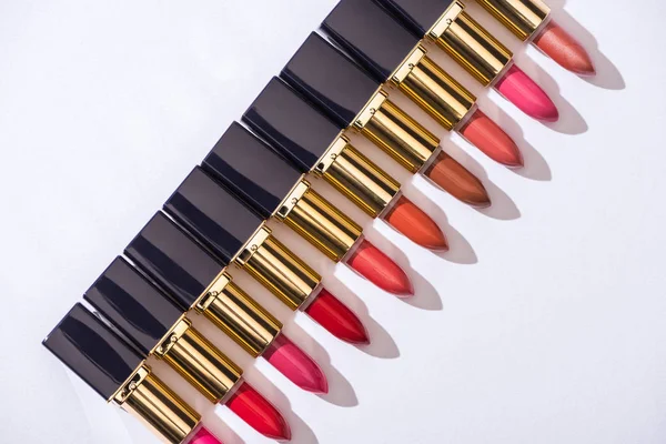 Draufsicht auf verschiedene Lippenstifte in Luxusröhren in einer Reihe auf weißem Hintergrund — Stockfoto