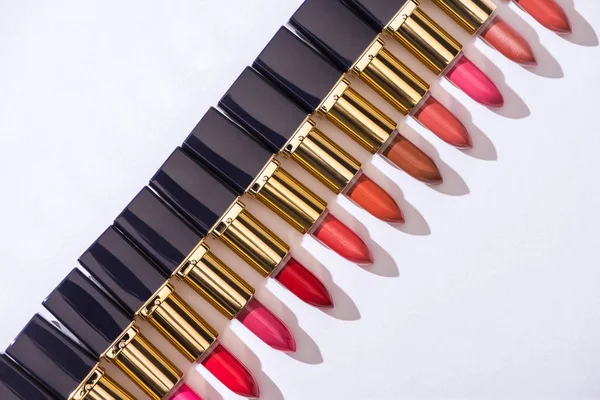 Top view of assorted lipsticks in luxury tubes in line on white background — Stock Photo