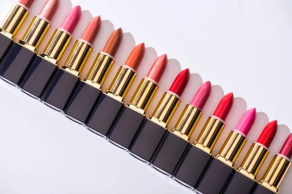 Top view of assorted lipsticks in luxury tubes in line on white background — Stock Photo
