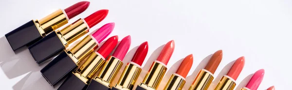 Top view of assorted lipsticks in luxury tubes on white background, panoramic shot — Stock Photo