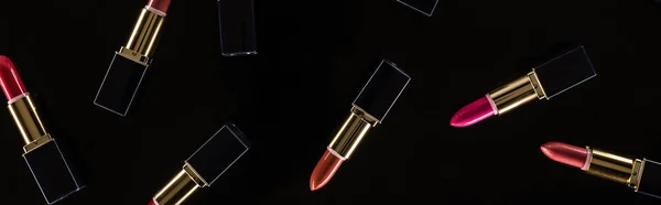 Top view of assorted lipsticks in luxury tubes isolated on black, panoramic shot — Stock Photo