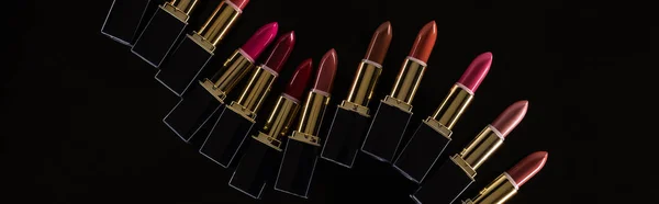 Vue de dessus de rouges à lèvres assortis dans des tubes de luxe isolés sur noir, panoramique — Photo de stock
