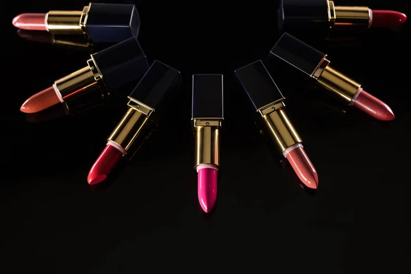 Assorted lipsticks in luxury tubes arranged in circle isolated on black — Stock Photo