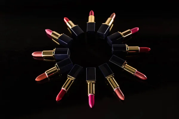 Assorted lipsticks in luxury tubes arranged in circle isolated on black — Stock Photo