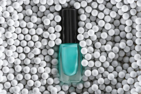 Vista superior de esmalte de uñas azul en botella entre perlas decorativas grises - foto de stock
