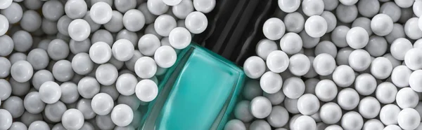 Top view of blue nail polish in bottle among grey decorative beads, panoramic shot — Stock Photo