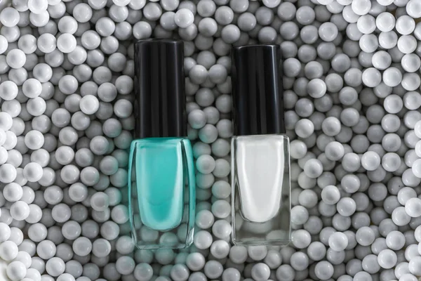 Верхний вид синего и белого лака для ногтей в бутылках в серых декоративных бусах — стоковое фото