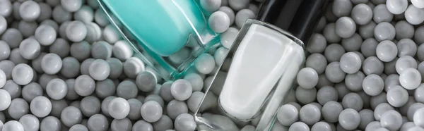 Top view of blue and white nail polish in bottles in grey decorative beads, panoramic shot — Stock Photo