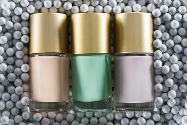 Vista superior del esmalte de uñas surtido en botellas en cuentas decorativas grises - foto de stock