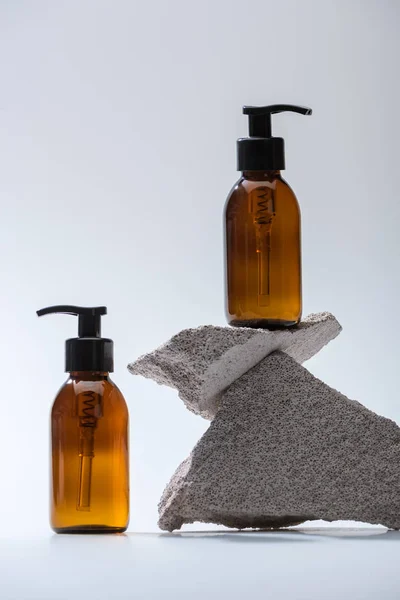 Bouteille cosmétique distributeur avec des pierres sur fond blanc avec contre-jour — Photo de stock