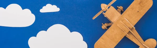 Draufsicht auf Holzflugzeug in blauem Himmel mit papiergeschnittenen weißen Wolken, Panoramaaufnahme — Stockfoto