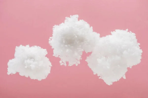 Nubes esponjosas blancas hechas de algodón aislado en rosa - foto de stock