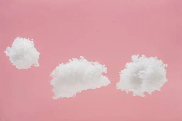 Nuvens fofas brancas feitas de lã de algodão isolado em rosa — Fotografia de Stock