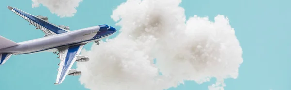 Spielzeugflugzeug fliegt inmitten weißer, flauschiger Wolken aus Watte isoliert auf blauem, panoramischem Foto — Stockfoto