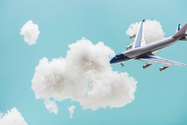 Avião de brinquedo voando entre nuvens brancas fofas feitas de lã de algodão isolado em azul — Fotografia de Stock