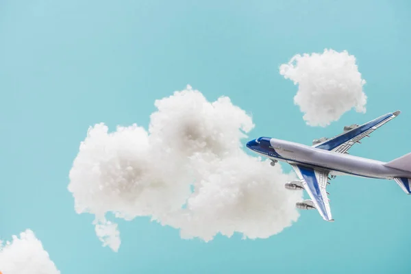 Jouet avion volant parmi les nuages duveteux blancs en laine de coton isolé sur bleu — Photo de stock