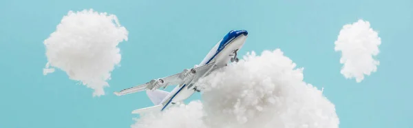 Avião de brinquedo voando entre nuvens brancas fofas feitas de lã de algodão isolado em azul, tiro panorâmico — Fotografia de Stock
