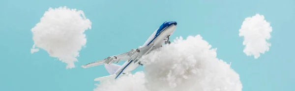 Avion jouet volant parmi les nuages pelucheux blancs en laine de coton isolé sur bleu, plan panoramique — Photo de stock